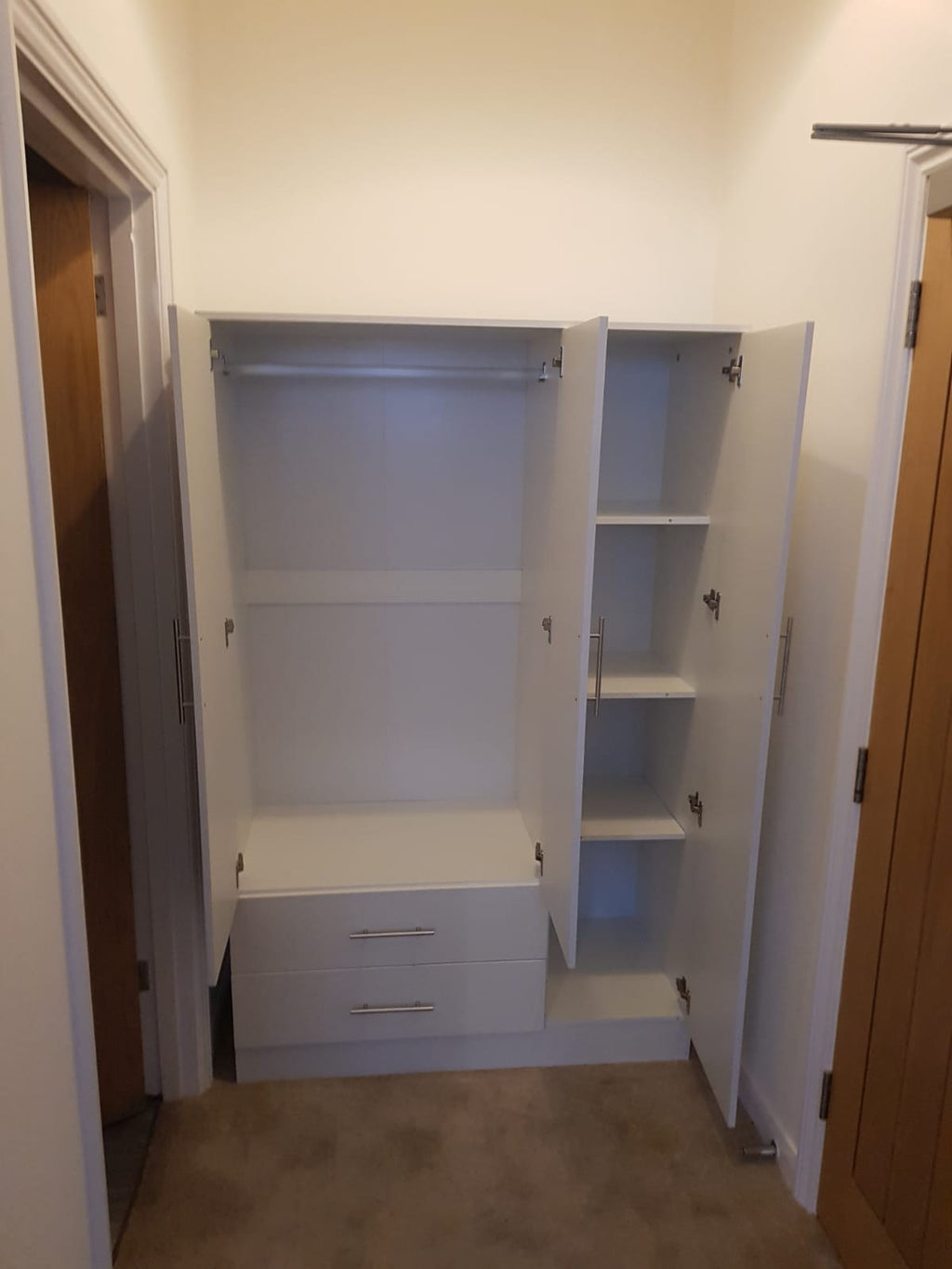 Inside a white 3-door wardrobe showing hanging rail and shelves