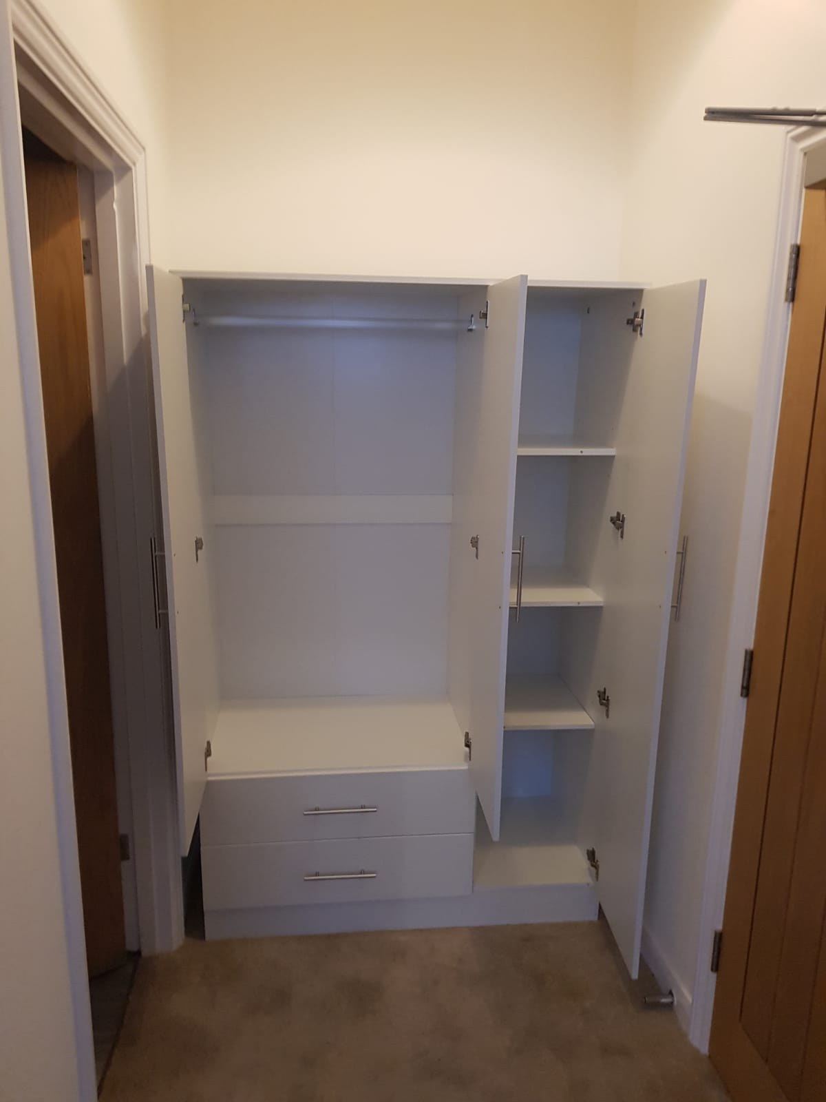 Inside a white 3-door wardrobe showing hanging rail and shelves